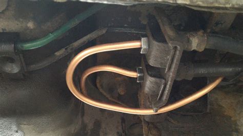 detailní fotografie měděného brzdového potrubí s improvizovaným úchytem