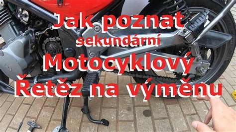 Detailní záběr na opotřebený motocyklový řetěz a rozetu.