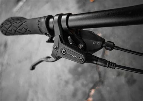 Detailní záběr na brzdový třmen hydraulické kotoučové brzdy s vyznačením šroubů pro seřízení