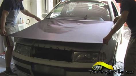 Ilustrace postupu vyhlazování fólie stěrkou od středu kapoty k okrajům.