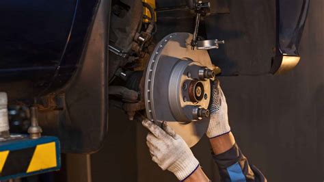 Detailní záběr mechanika montujícího pneumatiku na disk